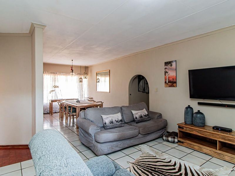 Spacious open-plan living and dining area featuring ceramic floor tiles, an arched doorway, and neutral wall finishes.