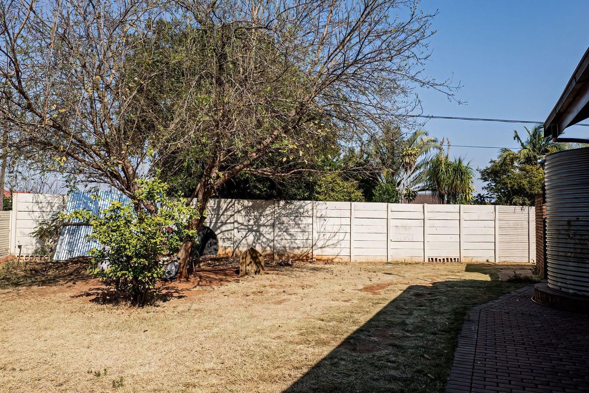 Rear garden area featuring a precast concrete boundary wall, a water tank, and a brick paved walkway.