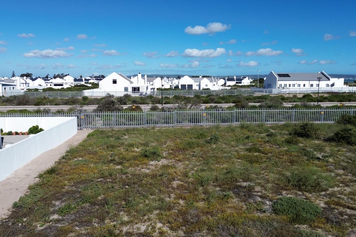 Aerial view of a vacant residential plot featuring perimeter fencing and surrounding neighborhood views.