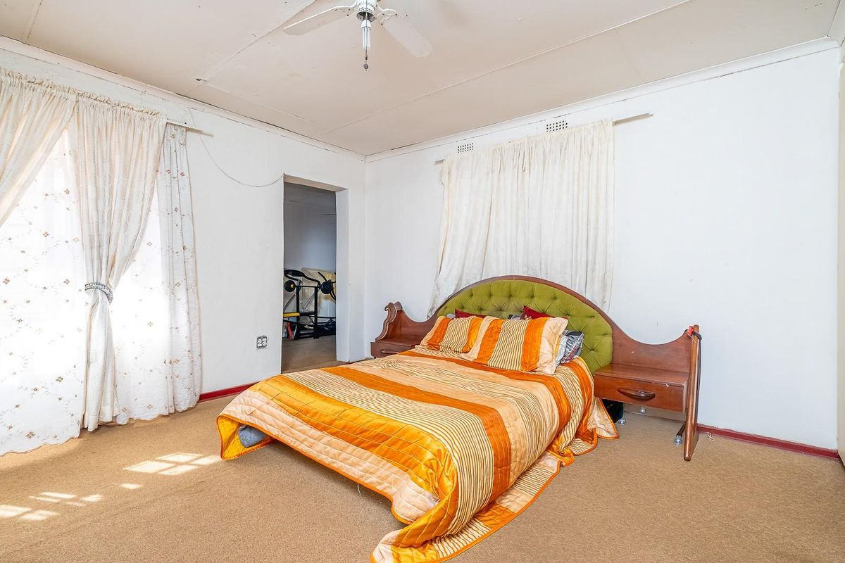 A spacious bedroom featuring a ceiling fan, built-in wardrobe, and carpeted flooring, offering a blank canvas for renovation and modernization.