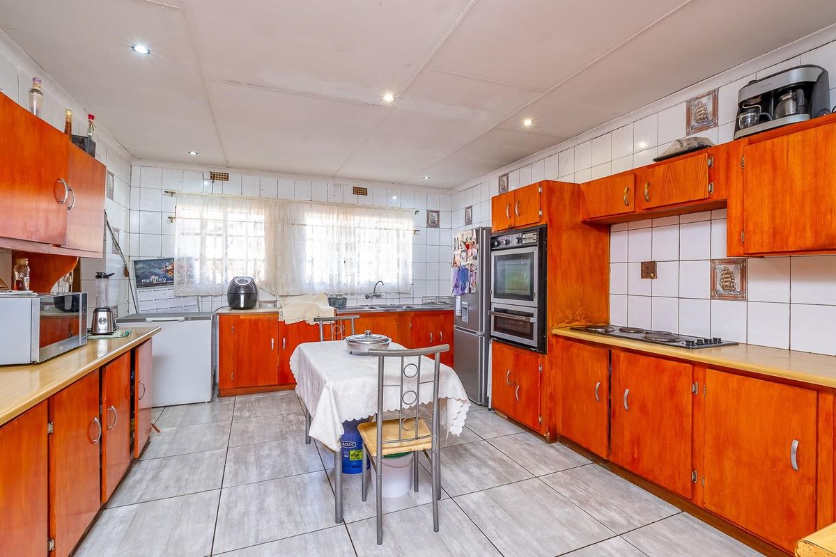 Spacious kitchen featuring extensive wooden cabinetry, built-in oven, hob, and tiled splashbacks, offering a functional layout with ample storage and preparation space.