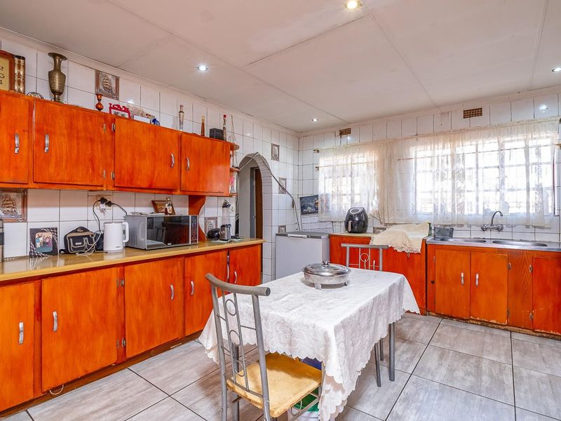 A dated kitchen featuring extensive wooden cabinetry, tiled splashbacks, and a double sink, offering significant potential for a modern renovation.