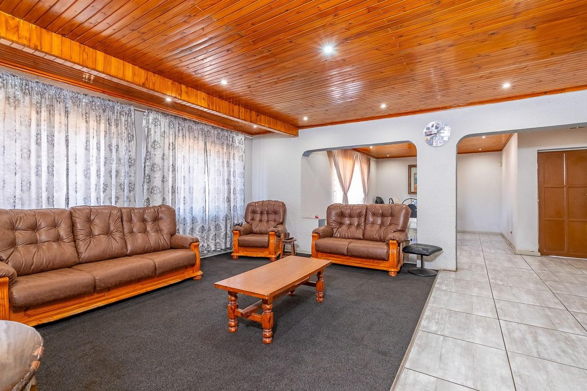 Spacious living room featuring a timber tongue and groove ceiling, recessed lighting, and a combination of carpeted and tiled flooring with an open archway.