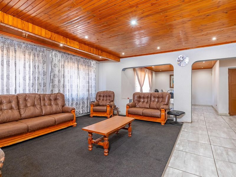Spacious living room featuring a timber tongue and groove ceiling, recessed lighting, and a combination of carpeted and tiled flooring with an open archway.
