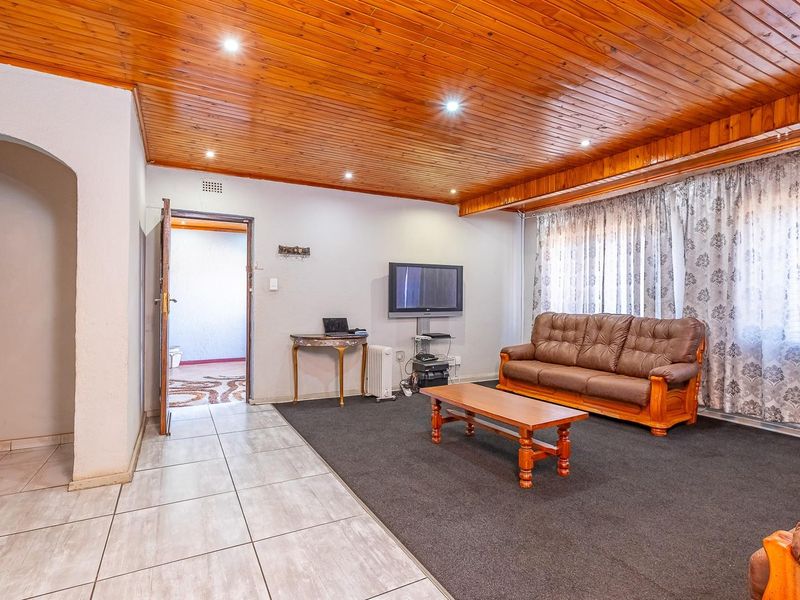 Spacious living room featuring a timber tongue and groove ceiling, recessed lighting, and a combination of tiled and carpeted flooring with an arched entryway.