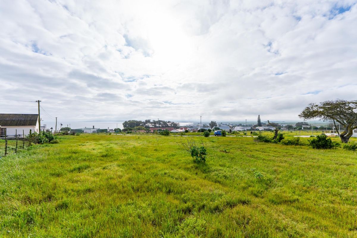 A vacant residential plot featuring open grassland, utility connections, and distant coastal views, offering a prime opportunity for new development.