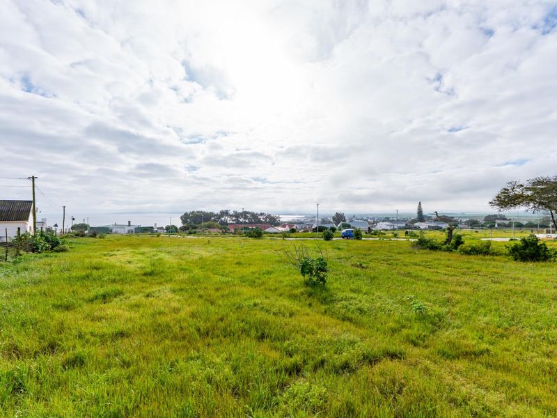 A vacant residential plot featuring open grassland, utility connections, and distant coastal views, offering a prime opportunity for new development.