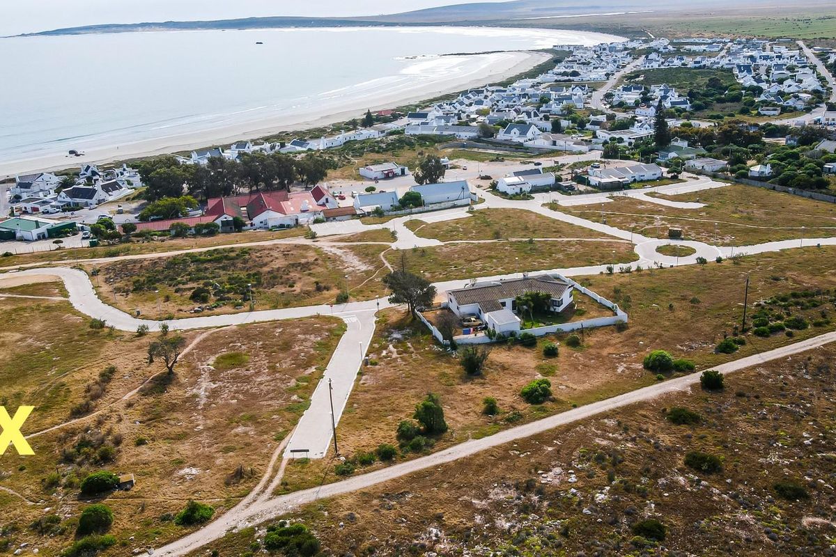 Aerial view of a residential land development situated near the coastline, featuring established access roads and proximity to the beach.