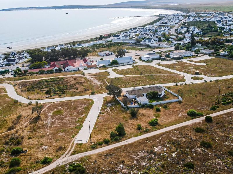 Aerial view of a residential land development situated near the coastline, featuring established access roads and proximity to the beach.