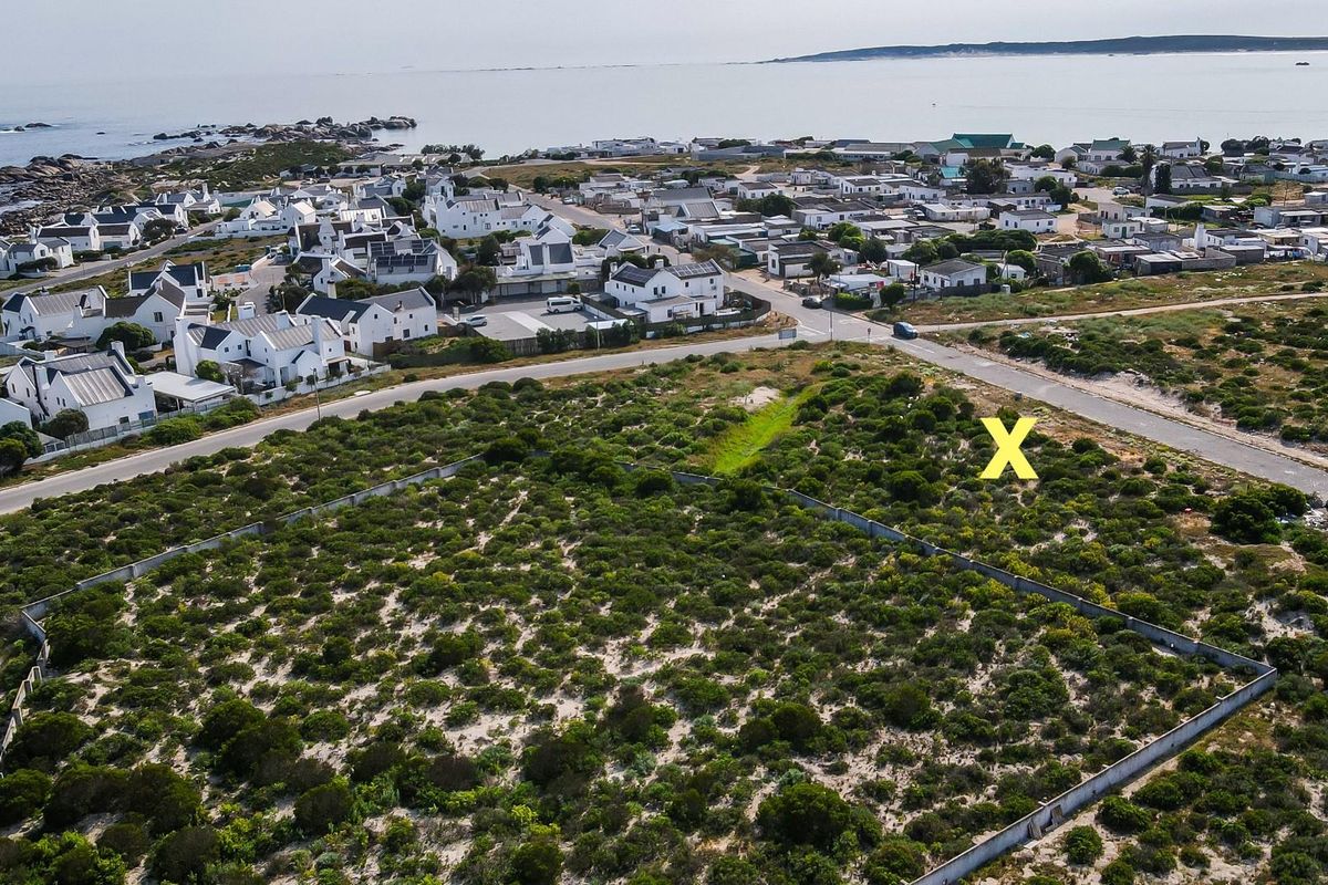 Aerial view of a vacant residential plot featuring boundary walls, situated in a coastal neighborhood with proximity to the ocean.