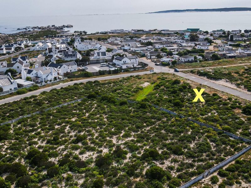 Aerial view of a vacant residential plot featuring boundary walls, situated in a coastal neighborhood with proximity to the ocean.