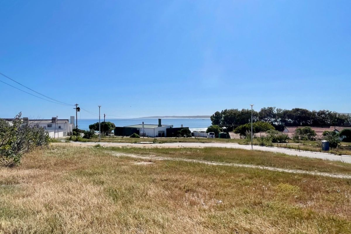 A view of the vacant residential land featuring coastal scenery, surrounding neighborhood infrastructure, and a paved access road.