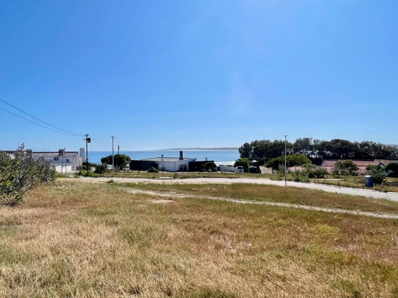 A view of the vacant residential land featuring coastal scenery, surrounding neighborhood infrastructure, and a paved access road.