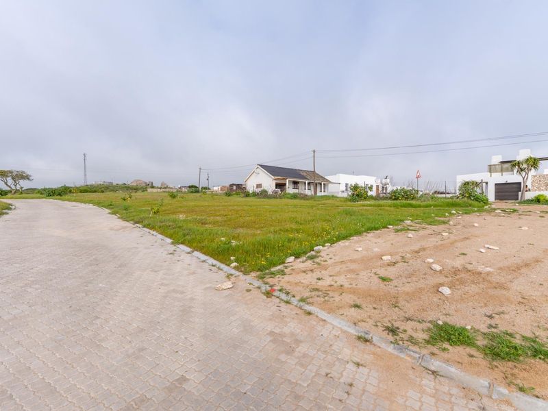 A vacant residential plot featuring a paved driveway, kerbing, and established surrounding neighborhood infrastructure.