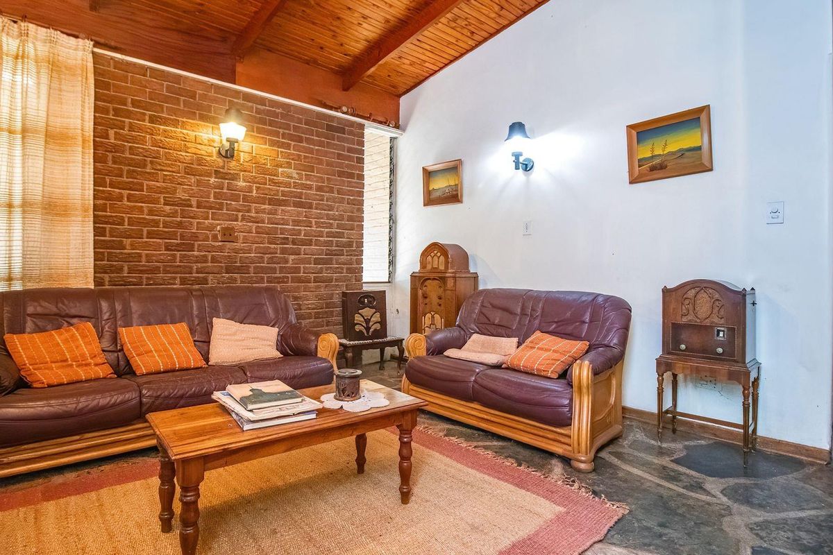 Living room featuring a rustic aesthetic with exposed brick walls, timber raked ceilings, and natural stone flooring.