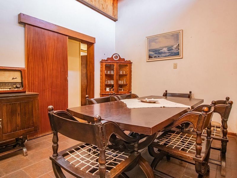 A dining room featuring timber wall paneling, tiled flooring, and a sliding timber door, offering a traditional aesthetic with potential for modernization.