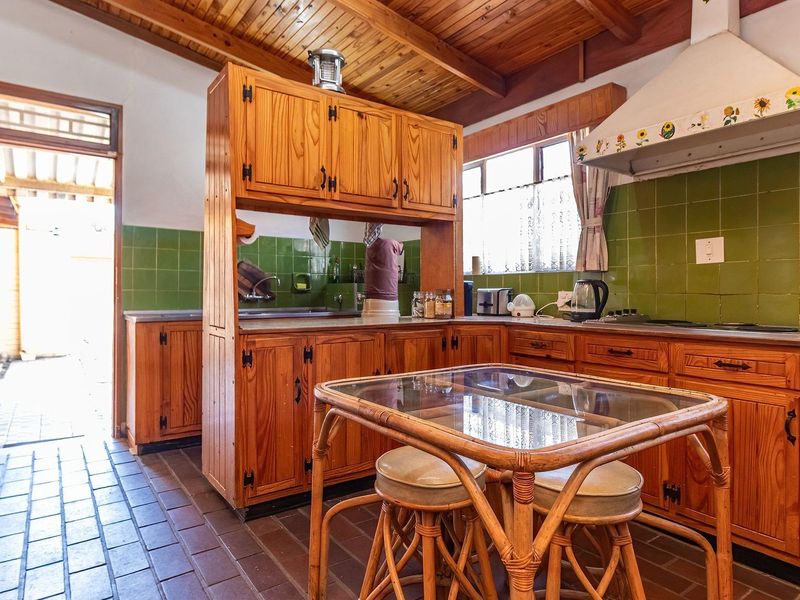 A traditional kitchen featuring timber cabinetry, a tiled splashback, and a vaulted timber ceiling, offering a classic aesthetic with potential for modern updates.