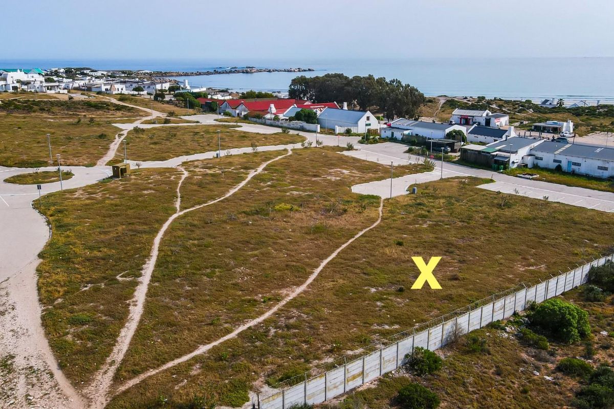 Aerial view of a vacant residential plot situated in a coastal estate, featuring established access roads and perimeter fencing.