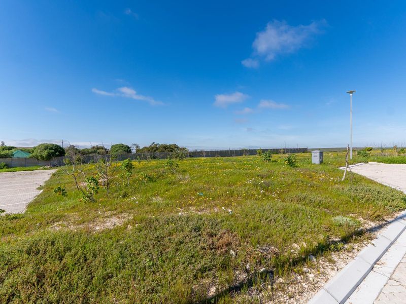 A vacant residential plot featuring established perimeter fencing, paved driveway access, and basic utility infrastructure, ready for development.