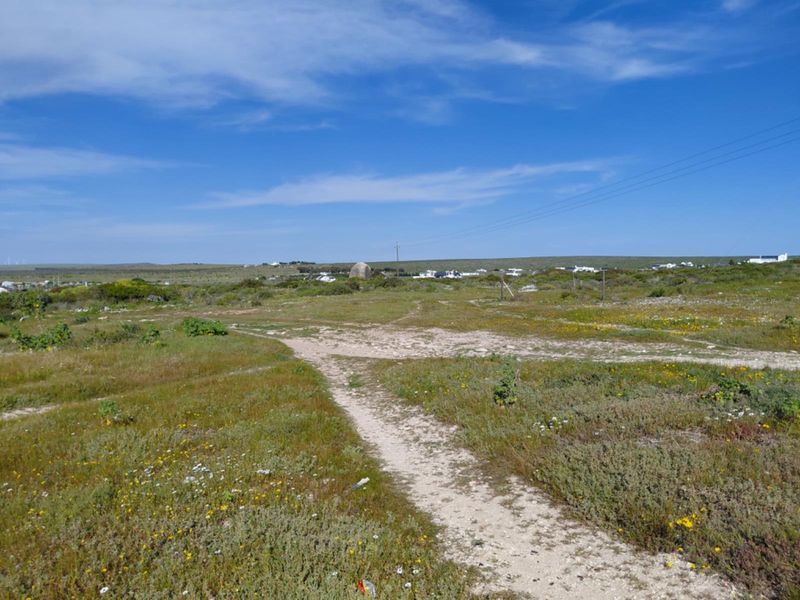 A view of an undeveloped residential plot featuring natural vegetation and a dirt path, suitable for future construction.