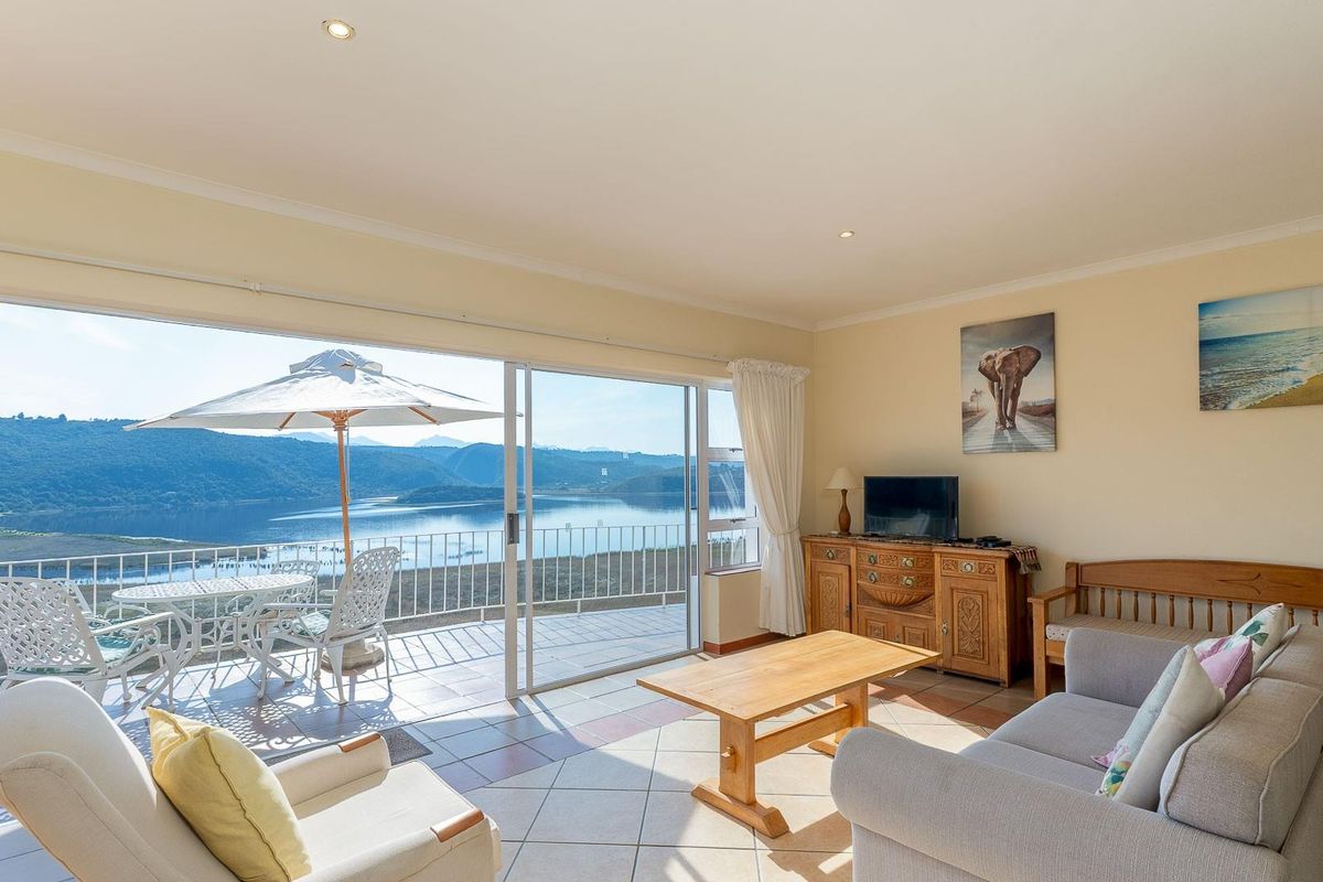 Spacious living room featuring large sliding glass doors that open onto a balcony with scenic water and mountain views.