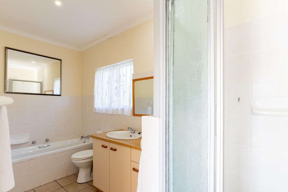 A functional bathroom featuring a built-in bathtub, separate shower enclosure, and a vanity cabinet with a ceramic sink.