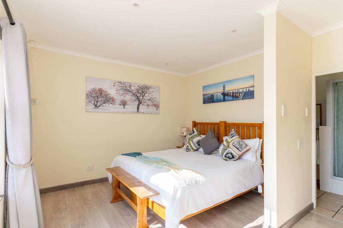 A well-maintained bedroom featuring laminate flooring, recessed lighting, and direct access to an en-suite bathroom.
