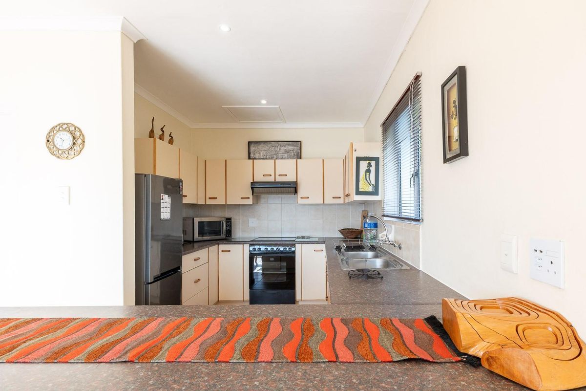 Functional kitchen featuring built-in cabinetry, laminate countertops, a stainless steel double sink, and a freestanding oven with an extractor fan.