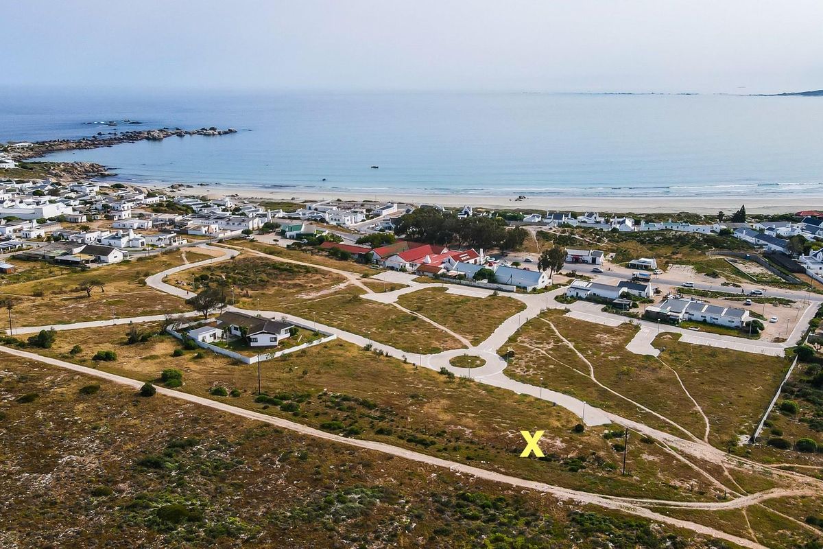 Aerial view of a residential vacant land plot located in a coastal development with established road infrastructure and proximity to the beach.