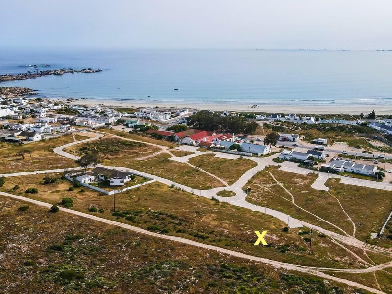 Aerial view of a residential vacant land plot located in a coastal development with established road infrastructure and proximity to the beach.