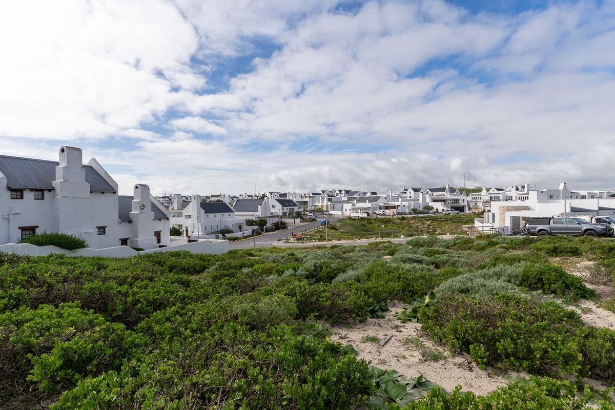A scenic view overlooking a residential estate with white coastal-style homes and surrounding natural vegetation.