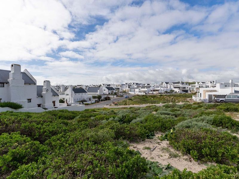 A scenic view overlooking a residential estate with white coastal-style homes and surrounding natural vegetation.