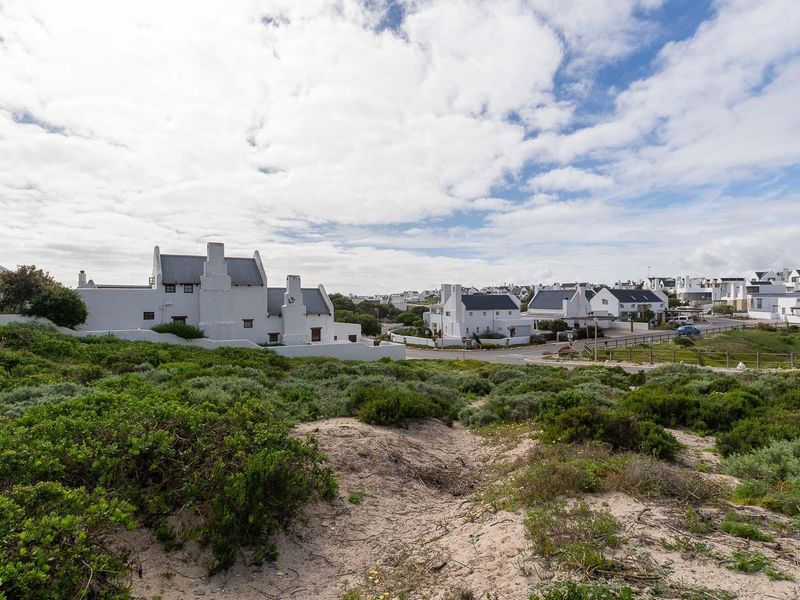 A scenic view of the surrounding residential estate featuring coastal vegetation and sand dunes in the foreground.