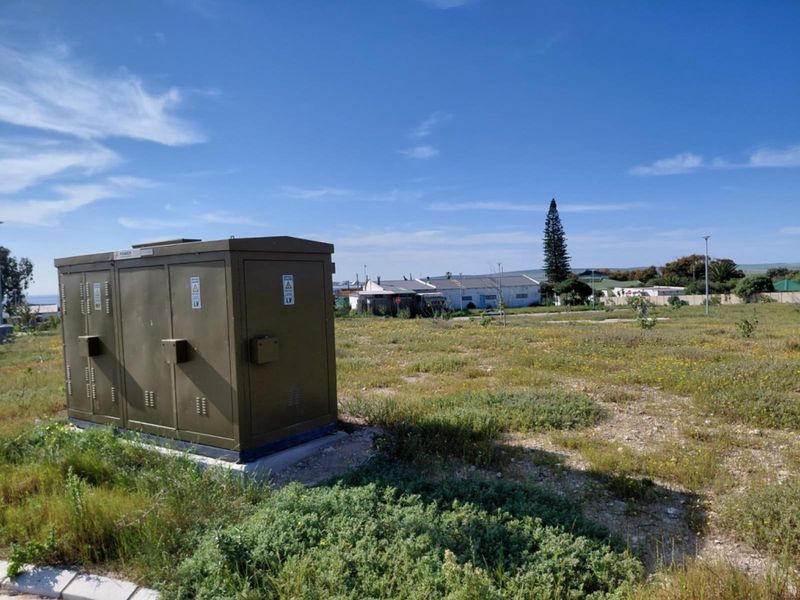 A vacant residential plot featuring a prominent electrical transformer box situated on the property boundary.