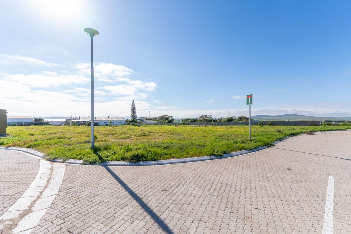 A vacant residential plot featuring paved street access, concrete curbing, and established street lighting, ready for development.