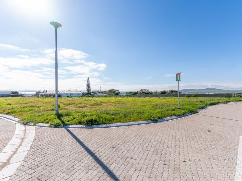 A vacant residential plot featuring paved street access, concrete curbing, and established street lighting, ready for development.