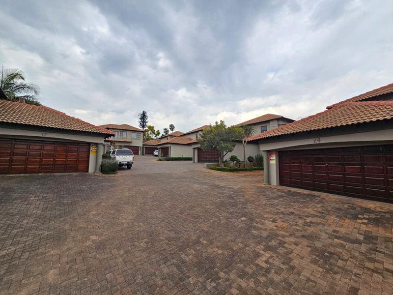 A view of the townhouse complex driveway featuring multiple garage entrances with tiled roofs and paved surfaces.