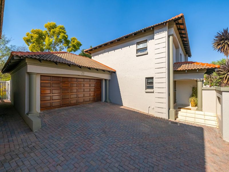 Front elevation of a townhouse featuring a double garage, paved driveway, and a covered entrance porch with decorative columns.