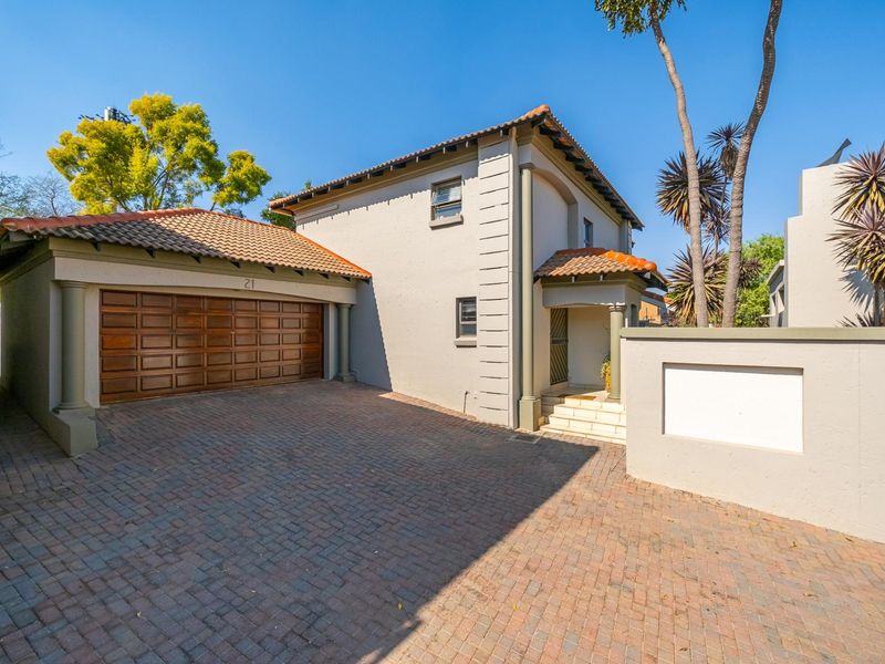Front elevation of a townhouse featuring a paved driveway, double garage with wooden door, and a covered entrance.