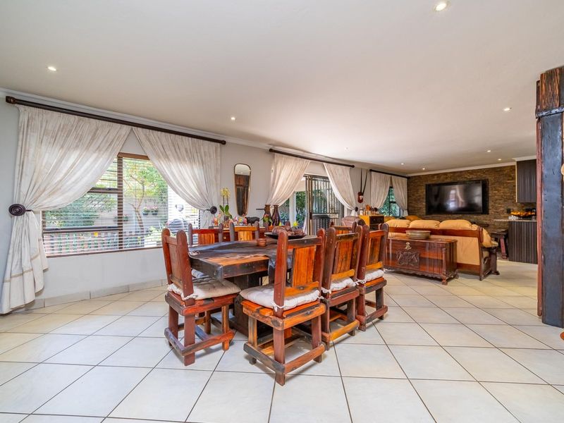 Spacious open-plan living and dining area featuring tiled flooring, recessed lighting, and a prominent stone feature wall.