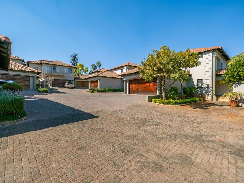 A view of the townhouse complex entrance featuring paved driveways, multiple garage access points, and well-maintained exterior facades with tiled roofing.