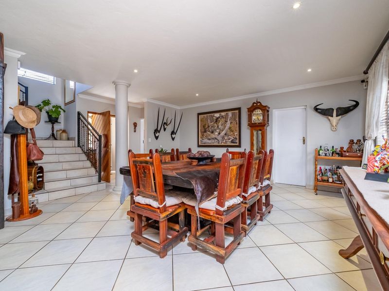 Spacious dining area featuring tiled flooring, recessed lighting, and an open-plan layout with an integrated staircase leading to the upper level.