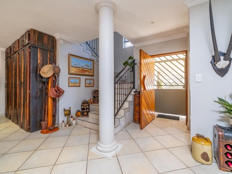 Welcoming entrance hall featuring tiled flooring, a central decorative column, and a staircase with a wrought iron balustrade leading to the upper level.