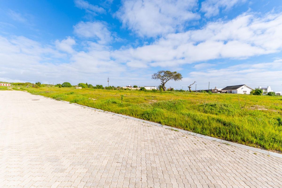 A view of a vacant residential plot featuring a paved road and concrete curbing, ready for development.