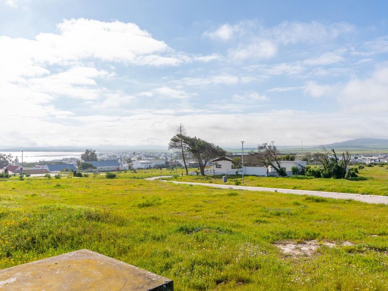 A wide-angle view of the vacant residential land, showcasing the surrounding neighborhood, coastal landscape, and existing infrastructure.