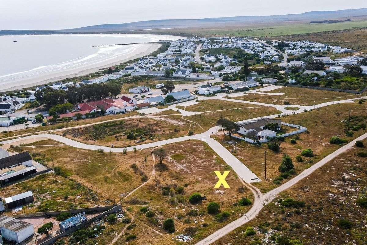 Aerial view of a vacant residential plot situated in a coastal neighborhood, offering proximity to the beach and established road infrastructure.