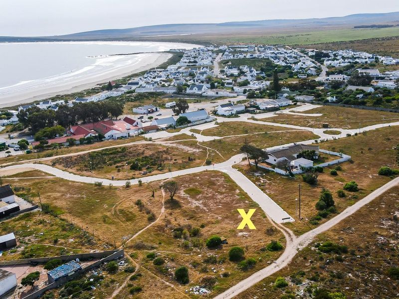 Aerial view of a vacant residential plot situated in a coastal neighborhood, offering proximity to the beach and established road infrastructure.