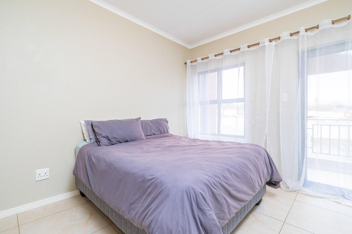 A bright bedroom featuring tiled flooring, a built-in cupboard, and a sliding glass door that provides access to an outdoor area.