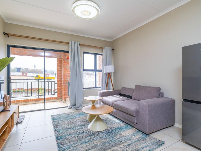 A bright living room featuring tiled flooring, a ceiling light fixture, and a sliding glass door providing access to an outdoor balcony area.