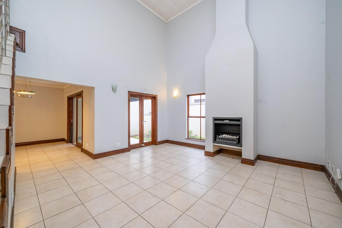Spacious living room featuring high vaulted ceilings, tiled flooring, and a built-in fireplace, offering a bright and open layout.